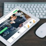A tablet with a financial website open, alongside a white keyboard and mouse. Ideal for tech-theme stock images.